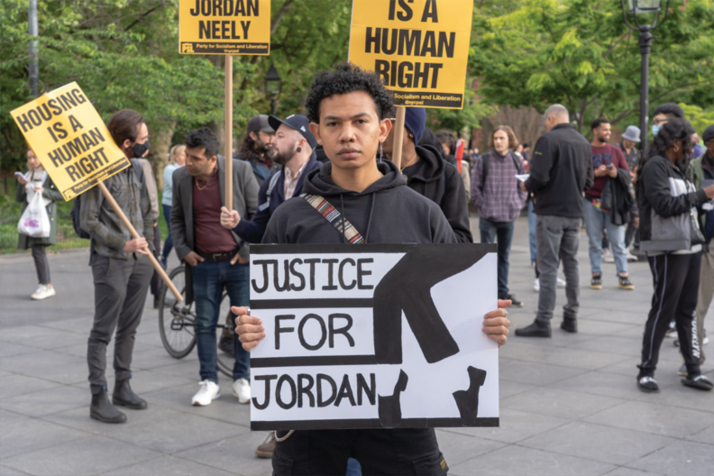 A young person at a protest holds a handmade sign that reads 