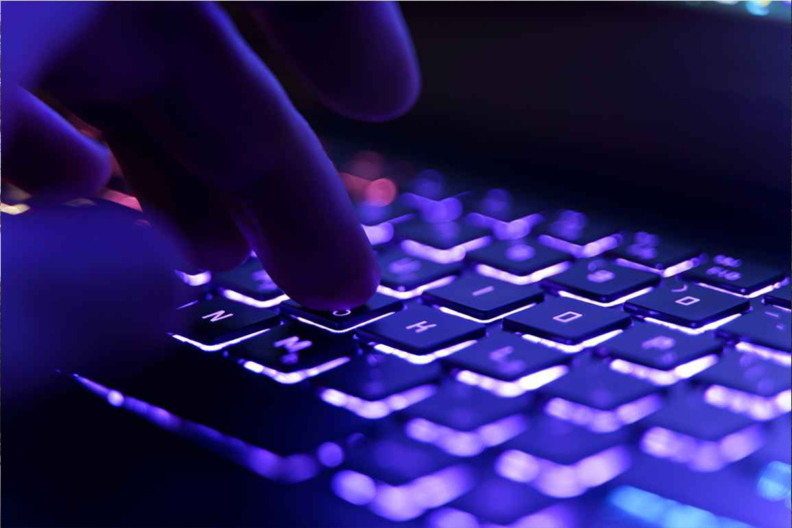 Hands touching a keyboard in dark purple light