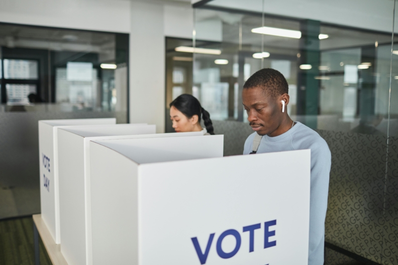 A person wearing ear pods in a voting booth